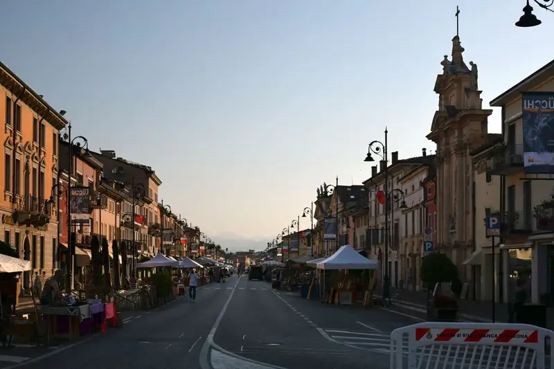 A vibrant street market in a European town at sunset, featuring architecture and food stalls.