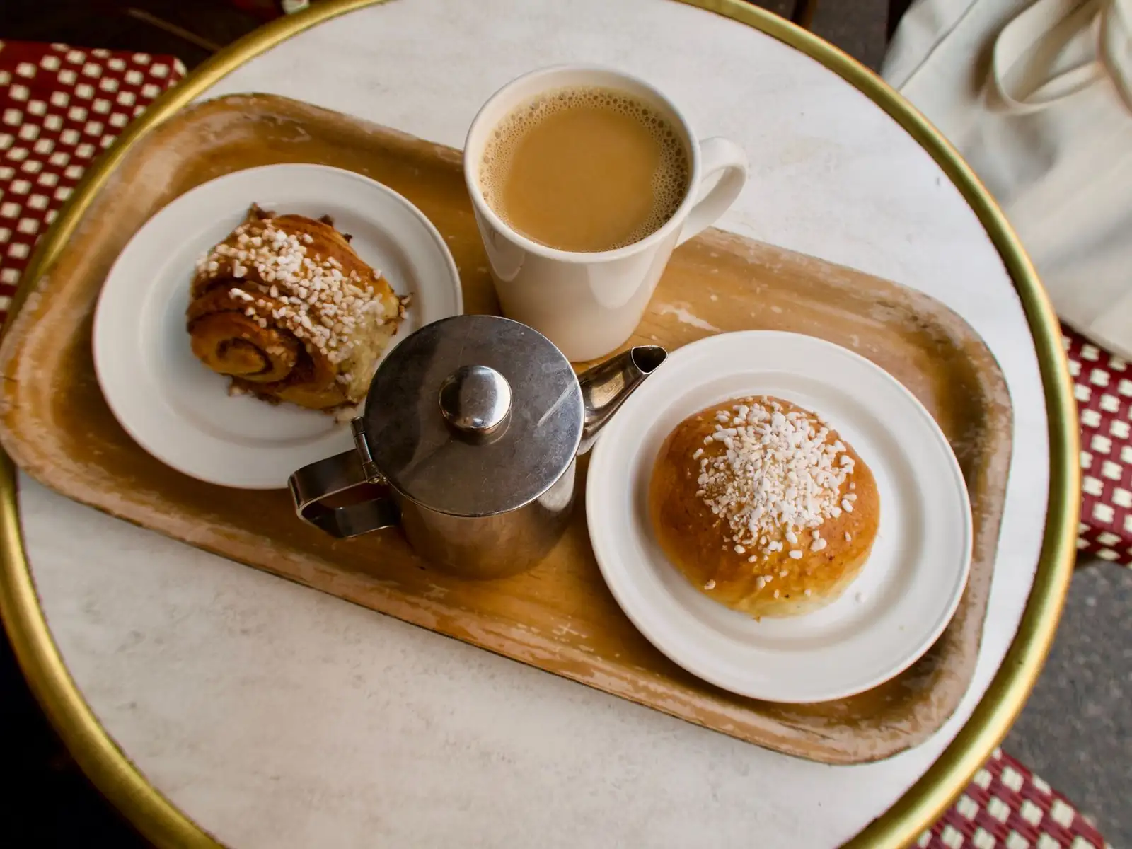 Enjoy a warm cup of coffee with cinnamon roll and bun on a cozy Helsinki caf茅 table.