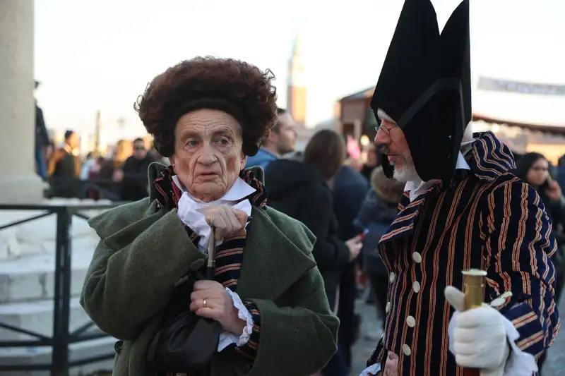 Two adults in elaborate Venetian costumes at the vibrant carnival in Venice, Italy.