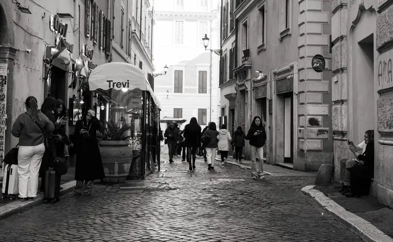 Black and white view of a bustling street near Trevi Fountain, Rome, Italy.