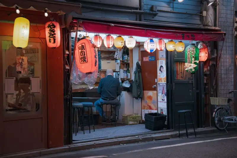 Nighttime view of a traditional yakitori shop in Tokyo, Japan, showcasing vibrant lanterns.