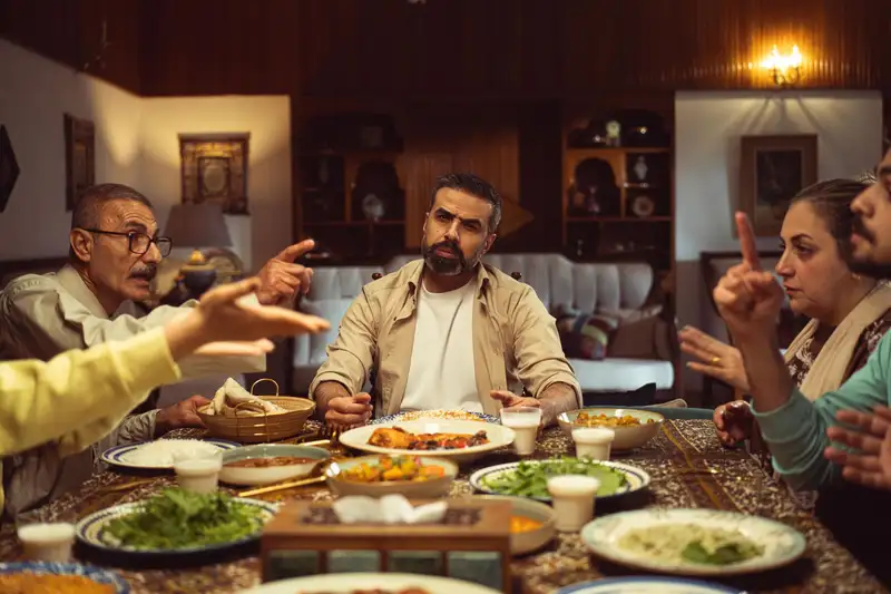 Family gathered around a dinner table, engaging in a lively conversation in a cozy dining room.